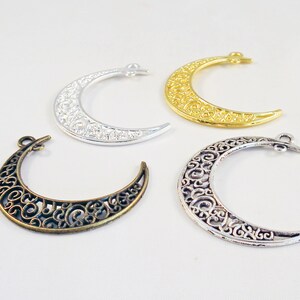 Peut inclure: Quatre breloques en métal en forme de croissant de lune ornées, en argent, or et bronze. Les breloques sont en filigrane et présentent un design délicat.