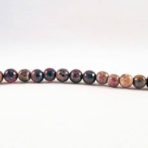 May include: A strand of brown, purple, and pink agate beads. The beads are round and have a mottled pattern.
