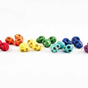 Peut inclure: Un assortiment de petites perles en forme de crâne arc-en-ciel. Les perles sont faites d'un matériau lisse et coloré et sont parfaites pour la fabrication de bijoux ou d'autres projets décoratifs.