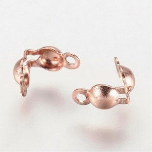 May include: Two rose gold metal clasps for jewelry making. Each clasp has a round ball on one end and a loop on the other end.