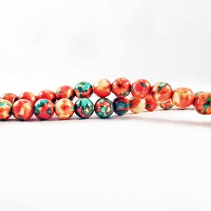 May include: A strand of colorful beads with a red, orange, and blue floral pattern. The beads are round and smooth.