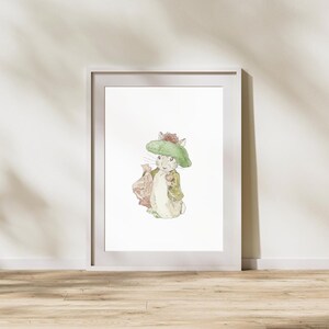 Puede incluir: Impresión en acuarela enmarcada de un personaje de conejo con sombrero y chaqueta verdes, llevando una bolsa y una manzana. La obra de arte está sobre un fondo blanco dentro de un marco blanco, evocando el estilo de ilustración de un libro infantil clásico.