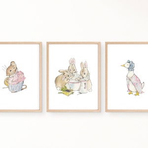 Puede incluir: Conjunto de tres láminas enmarcadas con ilustraciones de animales. Una lámina muestra un ratón con un vestido rosa, otra representa conejos y la tercera un pato con gorro y vestido. Las láminas están enmarcadas en madera.