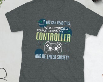 May include: A dark heather grey t-shirt with a graphic of a video game controller and the text "If you can read this I was forced to put down my controller and re-enter society."