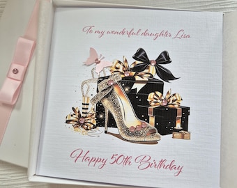 May include: A white card with a pink ribbon and a pink butterfly. The card has a gold and black shoe with a pink gem on it. The card says "To my wonderful daughter Lisa Happy 50th Birthday".