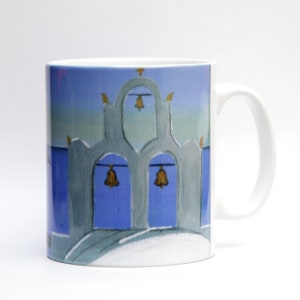 May include: White ceramic mug with a blue and gray illustration of a building with three arches and gold bells hanging from the arches. The sky is a light blue with a hint of green.