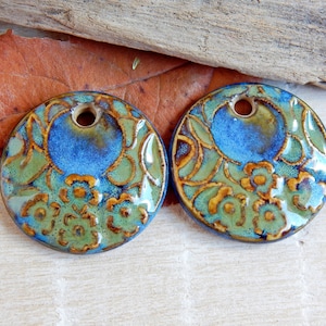 Peut inclure: Deux pendentifs ronds en céramique avec un motif floral bleu, vert et or. Chaque pendentif a un trou au centre pour l'accrocher.