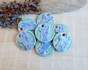 Puede incluir: Siete dijes redondos de cerámica con un esmalte iridiscente azul y verde. Cada dije presenta un diseño de hada estilizado con alas.