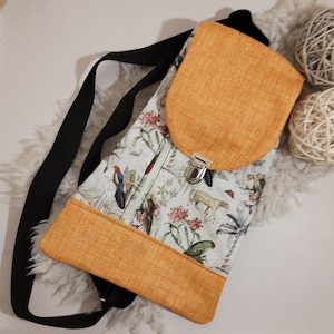 Può includere: Una piccola borsa a tracolla arancione e bianca con chiusura a lembo e cerniera. La borsa ha una stampa floreale con uccelli e animali. La tracolla è nera.