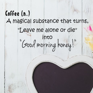 May include: A white heart-shaped chalkboard with a white frame, and the text "Coffee (n.) A magical substance that turns, 'Leave me alone or die' into 'Good morning honey!'" is displayed. A white pitcher with pink and white tulips is to the right.