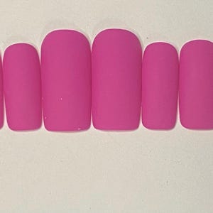 May include: Ten pink matte press-on nails in various sizes.
