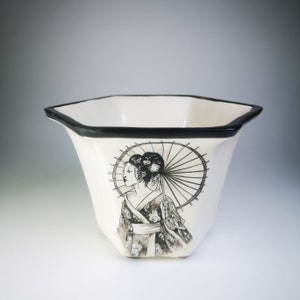 May include: White ceramic planter with a black rim and a black and white illustration of a woman with an umbrella. The woman is wearing a traditional Japanese kimono.