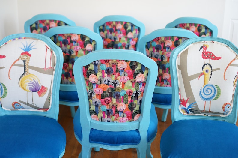 May include: Six turquoise blue chairs with different colorful patterned fabric upholstery. The chairs have a classic design with a curved back and a blue velvet seat.