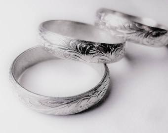 May include: Three silver rings with an intricate floral design.
