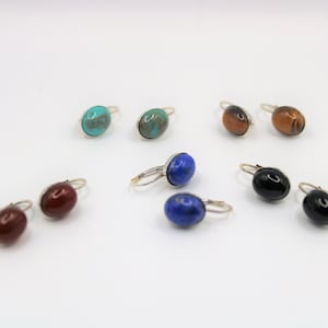 May include: A set of 10 silver earrings with various gemstone cabochons. The stones include turquoise, tiger's eye, carnelian, lapis lazuli, and onyx.