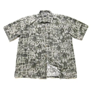 May include: Short-sleeved button-down shirt with a pattern of gray and black shapes on a light background. The shirt has a collared neckline and a button-up front. The fabric appears to be lightweight.