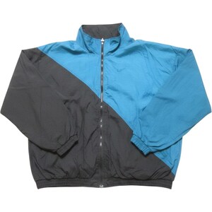 May include: A color-blocked windbreaker jacket featuring a diagonal design split between dark charcoal gray and bright teal blue. The jacket has a high collar, a full-length front zipper, long sleeves with elastic cuffs, and a small embroidered logo.