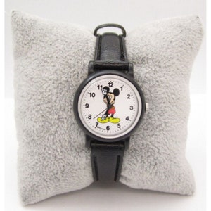 May include: Black leather wristwatch with a white face featuring Mickey Mouse playing golf. The watch has black hands and black numbers.