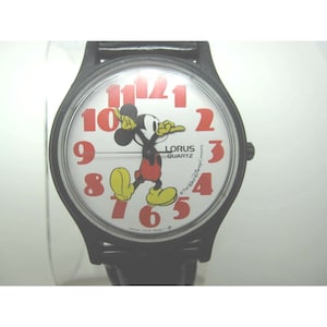 May include: Black wristwatch with a white face featuring Mickey Mouse and red numbers. The watch face also says "Lorus Quartz" and "The Walt Disney Company".