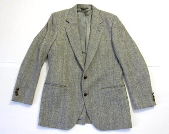 May include: A gray tweed blazer with a herringbone pattern and brown buttons. The blazer has a single breasted closure and two flap pockets.
