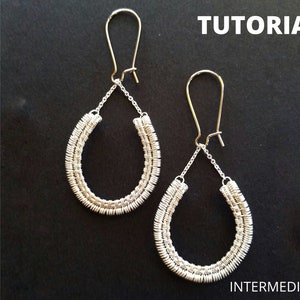 Peut inclure: Boucles d'oreilles en forme de goutte d'eau, argentées, enveloppées de fil de fer, avec des crochets d'oreilles dorés. Les boucles d'oreilles sont reliées par une chaîne délicate. Le mot "TUTORIAL" est en haut et "INTERMEDIATE" en bas.