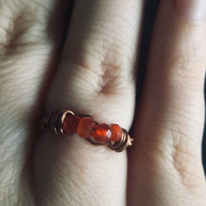 May include: A copper wire ring with orange carnelian stones.