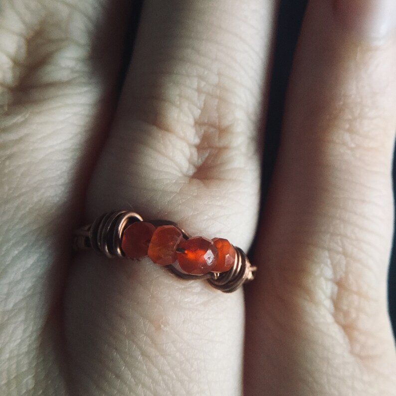 May include: A copper wire ring with orange carnelian stones.