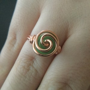 K&ouml;nnte beinhalten: Ein Ring aus Kupferdraht mit einem gr&uuml;nen Glas-Spiralendesign.