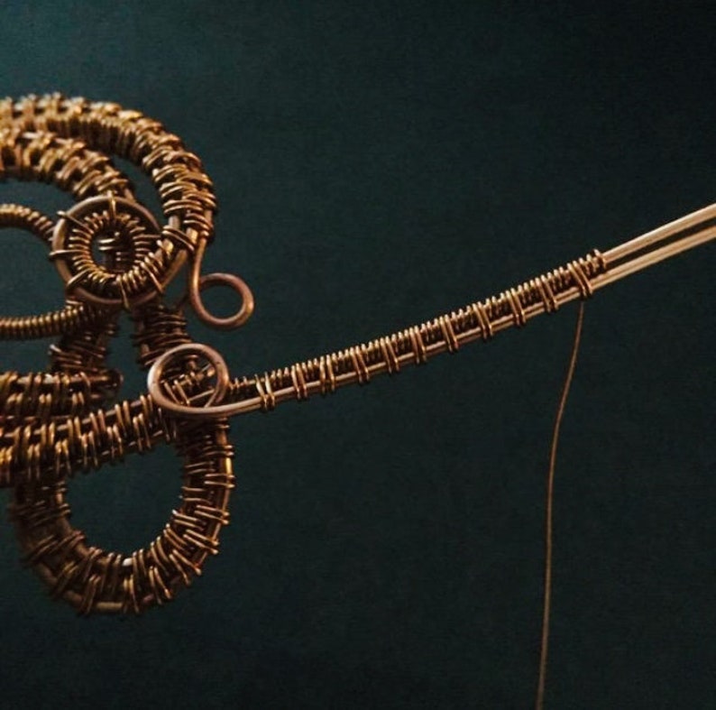 K&ouml;nnte beinhalten: Nahaufnahme einer Skulptur aus Kupferdraht mit komplizierten gewebten Mustern. Die Skulptur besteht aus d&uuml;nnem Kupferdraht und hat eine zarte, organische Form.