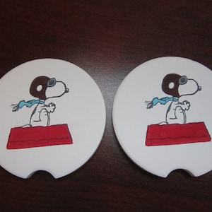 Set of 2 Snoopy car coasters for your cup holders. Featuring the Peanuts dog Snoopy as the Flying Ace!
