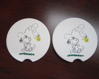 Set of 2 Snoopy & Woodstock car coasters for your cup holders. Featuring the joyful spirited Peanuts dog and his bird pal.