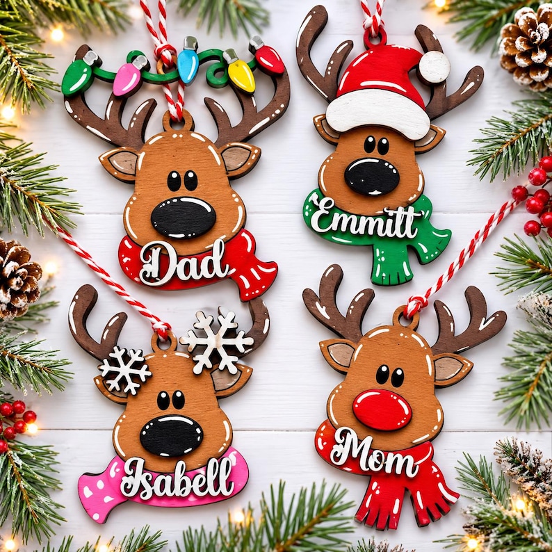 Pu&ograve; includere: Quattro decorazioni a forma di renna in legno con cordino rosso e bianco. Una ha una sciarpa rossa con la scritta Dad, una verde con Emmitt, una rosa con Isabell e una rossa con Mom. Ognuna presenta dettagli come luci natalizie, un cappello da Babbo Natale o fiocchi di neve bianchi.