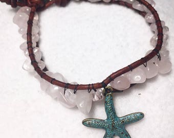 May include: A brown leather bracelet with pink and white stones and a turquoise blue starfish charm.