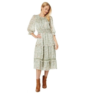 Könnte beinhalten: Ein grünes Blumen-Midi-Kleid mit einem Stufenrock und 3/4-Ärmeln. Das Kleid hat einen figurbetonten Oberteil und einen lockeren Rock.