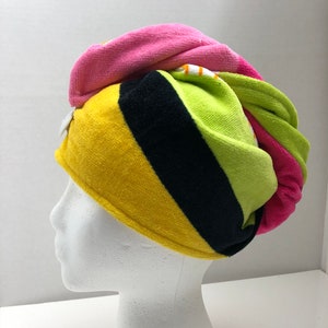 May include: A colorful striped hair towel in pink, yellow, green, and black. The towel is wrapped around a white mannequin head.