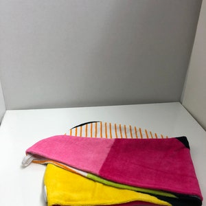 May include: A colorful hooded towel with a striped pattern in white, orange, and black. The towel is folded in half and has a pink, yellow, and green section.