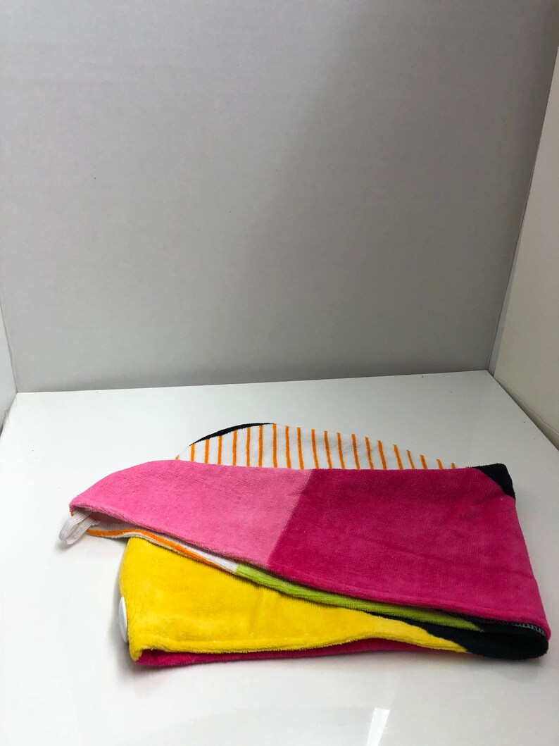 May include: A colorful hooded towel with a striped pattern in white, orange, and black. The towel is folded in half and has a pink, yellow, and green section.
