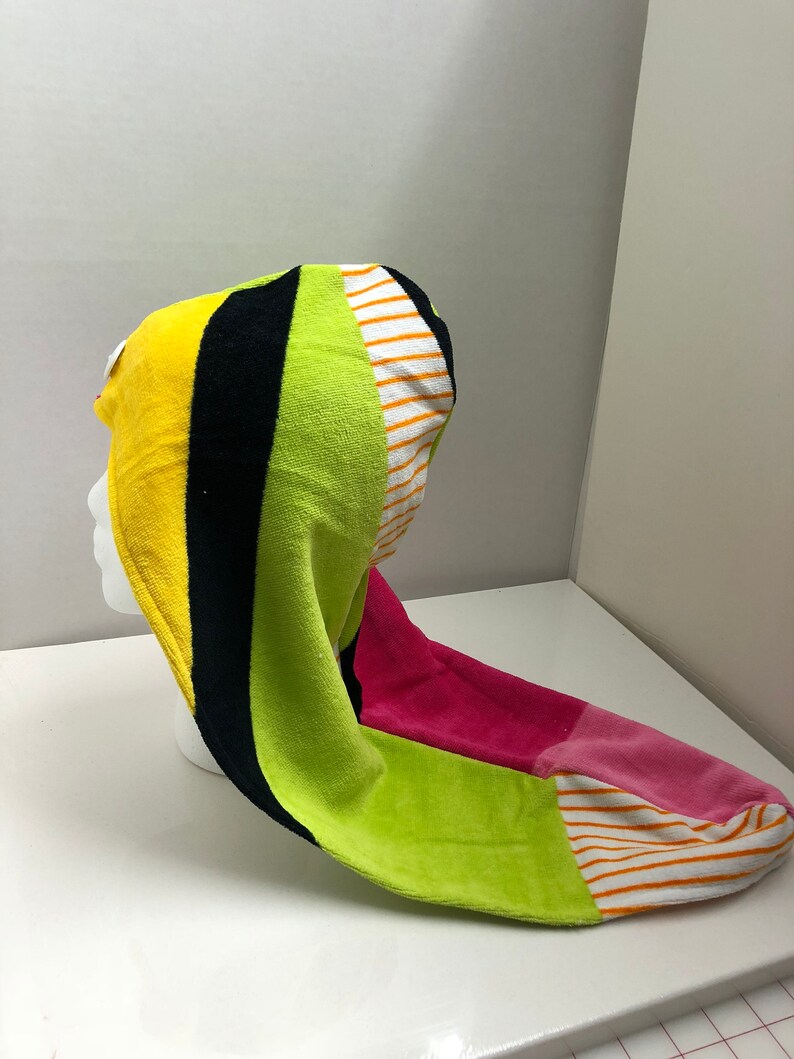 May include: A colorful hooded towel with stripes of yellow, black, green, pink, and white.