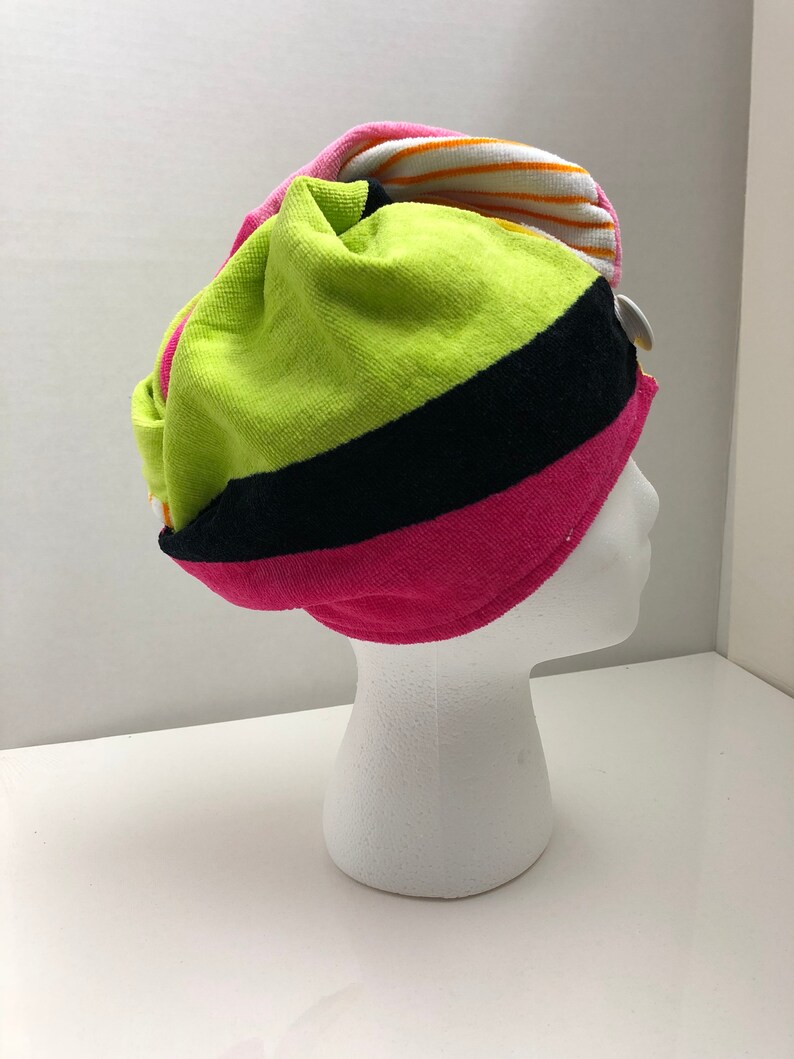 May include: A colorful striped towel turban in pink, green, black, white, and orange. The turban is made of soft, absorbent material and is designed to help keep hair dry after showering.