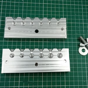 Puede incluir: Dos moldes de metal plateado para fundir plomos de pesca. Cada molde tiene seis cavidades para crear diferentes tamaños de plomos. También se incluye una tuerca y una arandela de metal plateado.