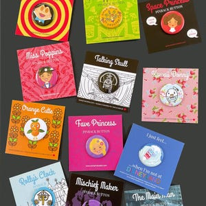 Puede incluir: Una colecci&oacute;n de doce botones con dise&ntilde;os variados, incluyendo personajes y frases. Cada bot&oacute;n se muestra en una tarjeta colorida. El texto "The Cutest Buttons" y "12 Styles to Choose From!" est&aacute;n en la parte superior. El logotipo de la marca est&aacute; en la parte inferior.