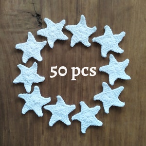 May include: Fifty white crocheted star shapes arranged in a circle on a wooden surface.