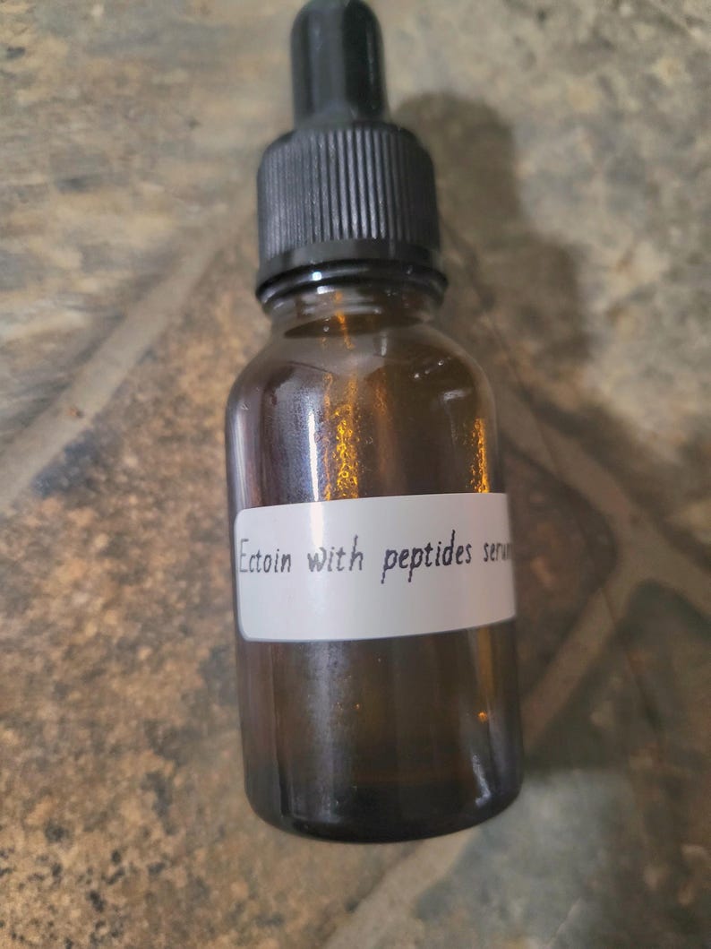 May include: A brown glass bottle with a black dropper top. A white label on the bottle reads "Ectoin with peptides serum". The bottle is likely for skincare products.