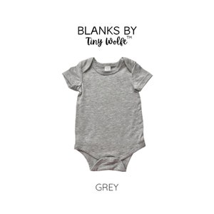 May include: Grey short-sleeved baby bodysuit with a crew neck. The bodysuit is blank and has the text "Blanks by Tiny Wolfe" above it.
