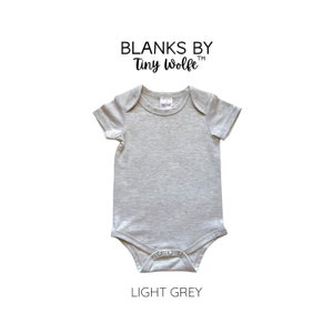May include: Light grey baby onesie with short sleeves and a snap closure. The onesie is made of a soft, comfortable fabric and is perfect for everyday wear. Blanks by Tiny Wolfe.