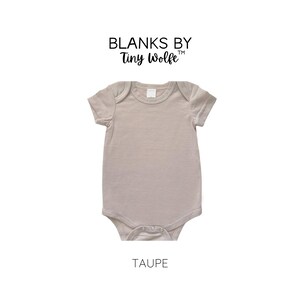 May include: A taupe short-sleeve baby onesie with snaps at the bottom. Blanks by Tiny Wolfe is printed on the top of the onesie.