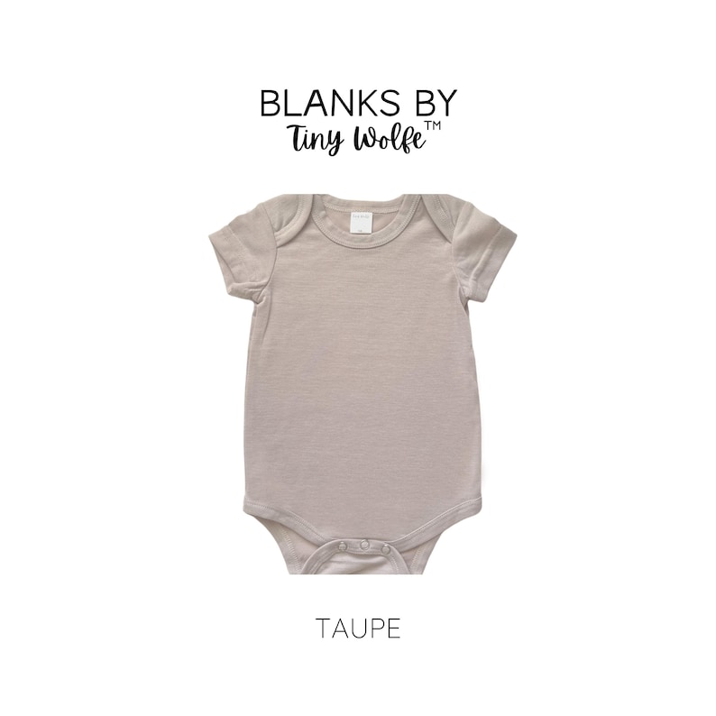 May include: A taupe short-sleeve baby onesie with snaps at the bottom. Blanks by Tiny Wolfe is printed on the top of the onesie.