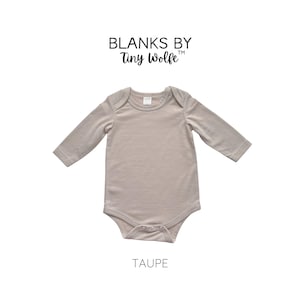 K&ouml;nnte beinhalten: Ein lang&auml;rmliger, taupefarbener Baby-Body mit Rundhalsausschnitt und Druckkn&ouml;pfen. Der Body ist von Blanks by Tiny Wolfe.