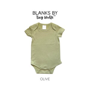 May include: A plain olive green baby onesie with short sleeves and a snap closure. The onesie is made by Blanks by Tiny Wolfe.