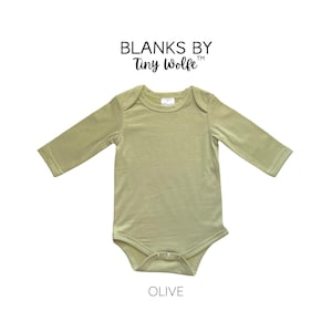 K&ouml;nnte beinhalten: Ein lang&auml;rmliger Baby-Body in hellgr&uuml;n, beschriftet mit "Olive". Der Body ist von Blanks by Tiny Wolfe.